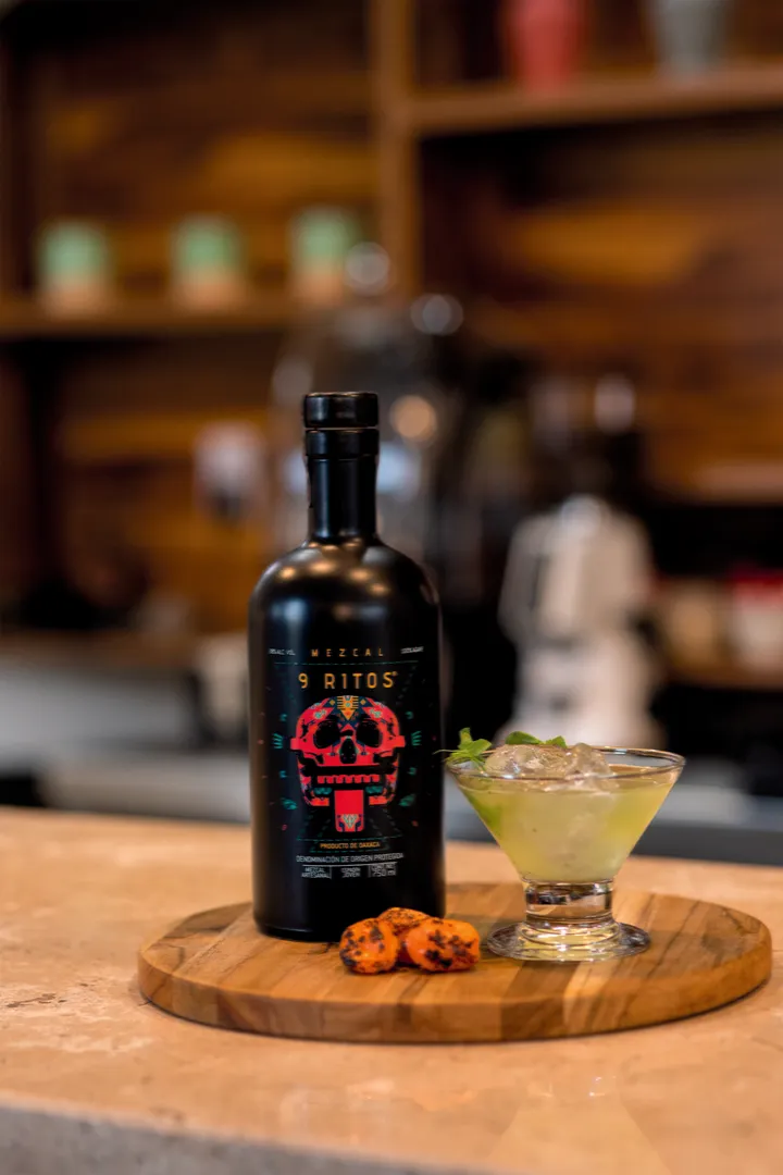 Bottle of Mezcal 9 Ritos on a bar with a cocktail